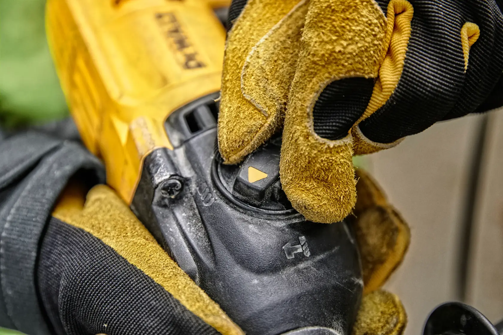 A close-up view of a gloved hand adjusting the mode selector on a DEWALT power tool, showing the yellow and black tool body and the control dial.