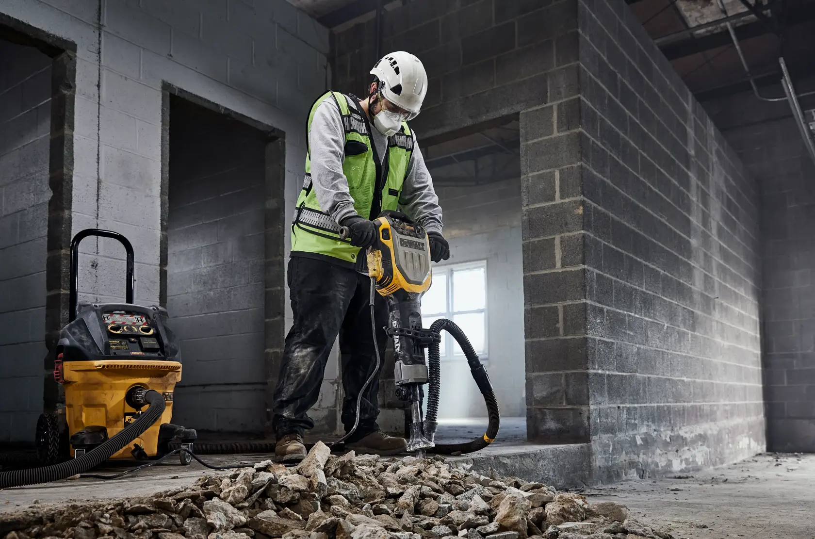 Worker uses DEWALT D25966, D25966-B2 breaking tool on debris. Construction site background.