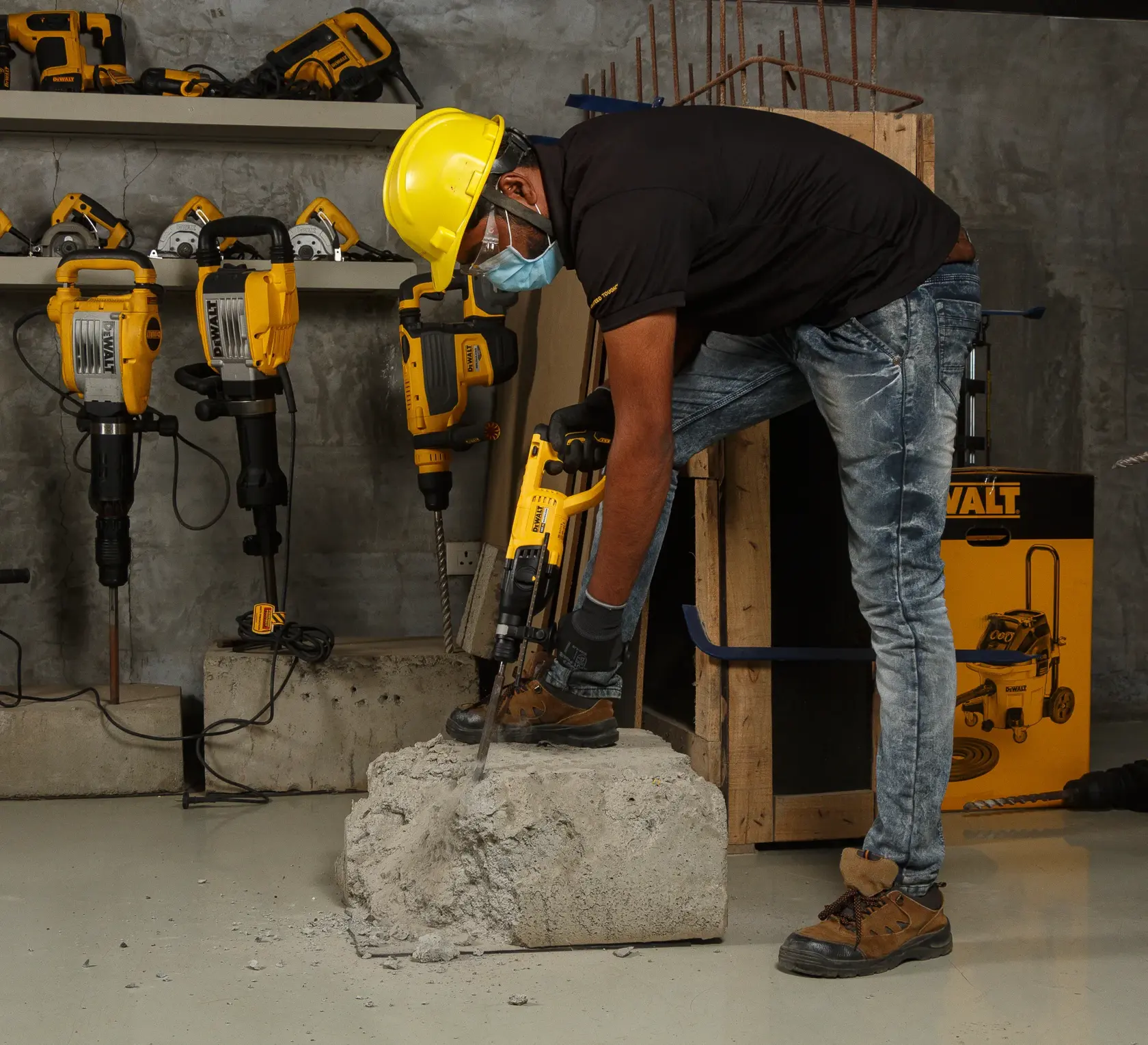 Trabajador usa martillo DEWALT en concreto con equipo de seguridad. Otros DEWALT visibles en los estantes.