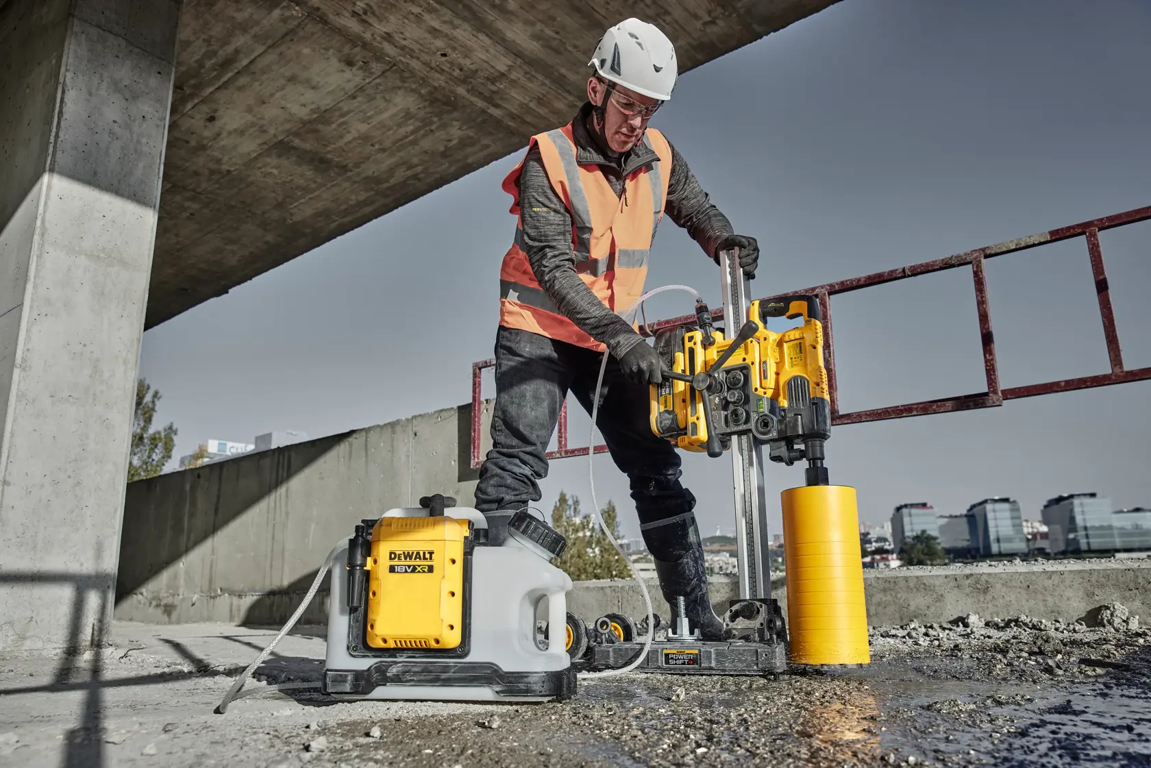 A DEWALT core drill machine with a yellow motor unit mounted on a vertical metal rail and a base with wheels for mobility.