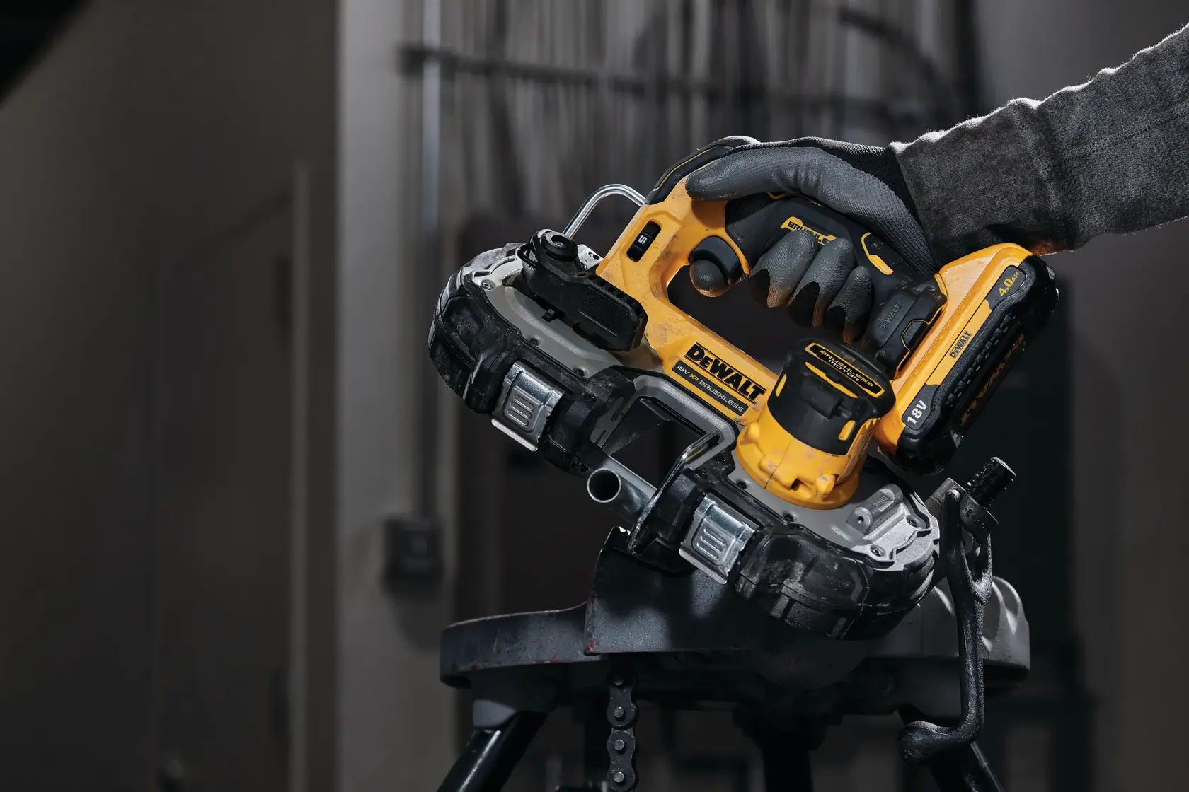 A DEWALT handheld bandsaw cutting metal tubing in an industrial setting. Gloved hand holds the tool.