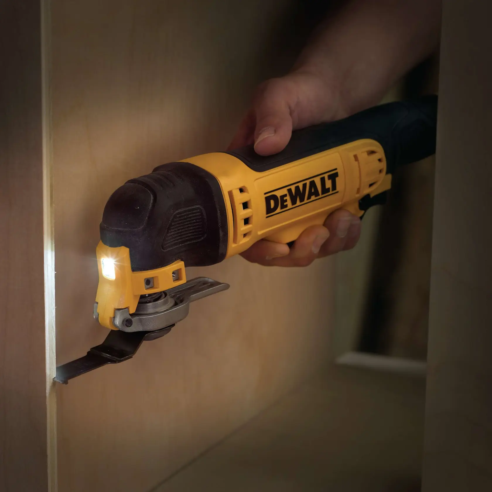DEWALT Multitool schneidet Holz mit Klinge, von Hand gehalten. Gelb-schwarz mit LED-Licht.