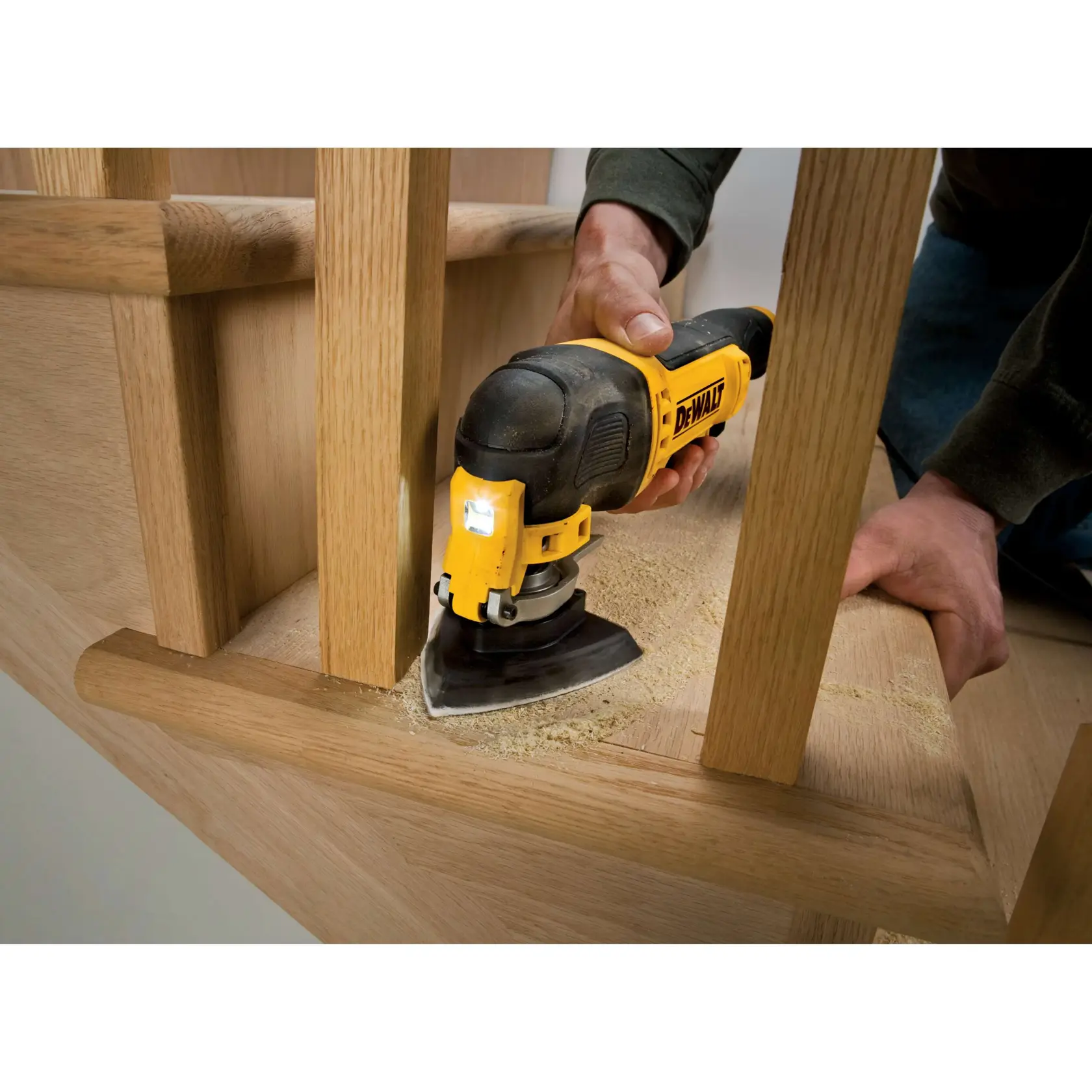 Herramienta DEWALT lijando escalera de madera, sostenida por persona, polvo en el proceso.