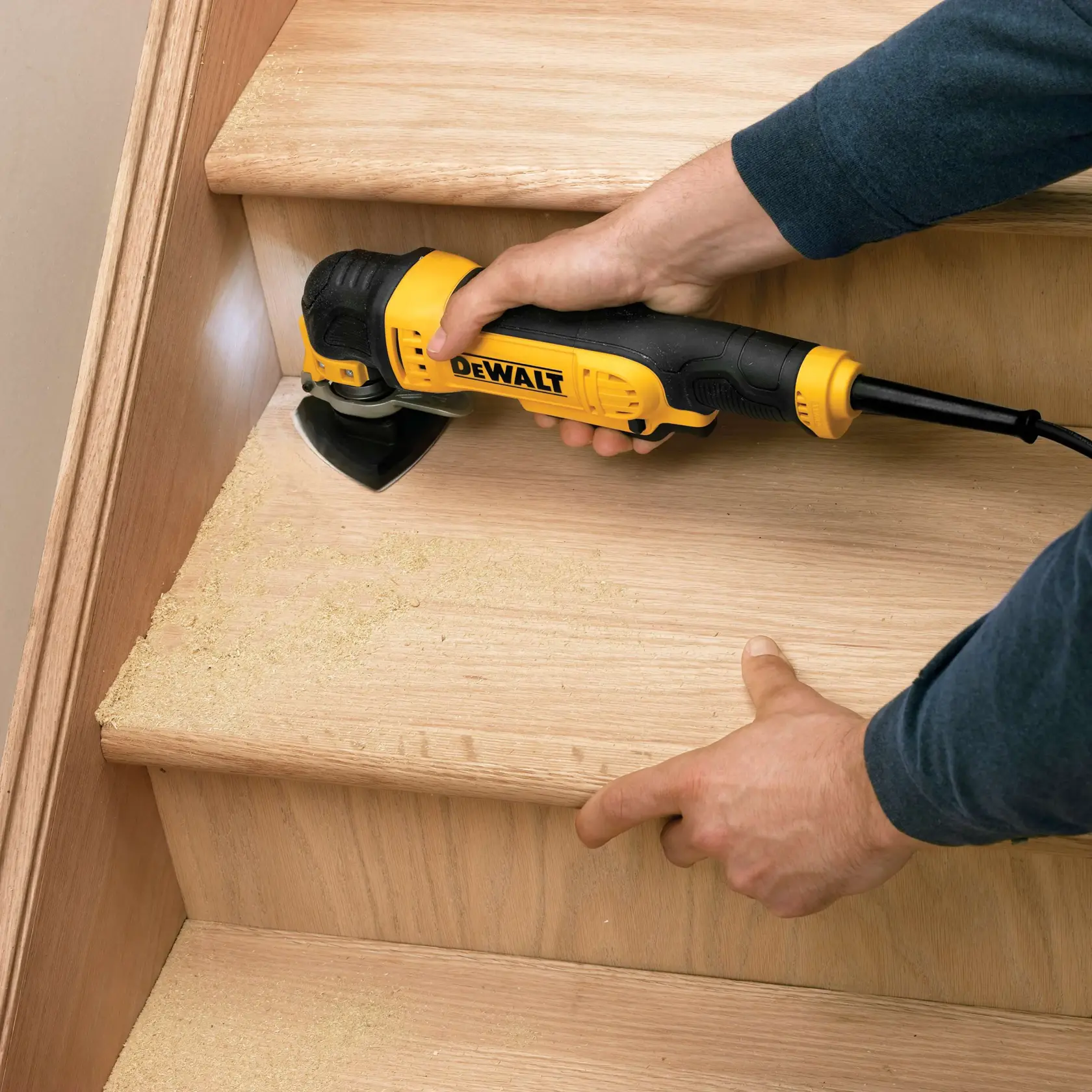 Herramienta DEWALT DT3093 lijando una escalera de madera, generando polvo fino en los peldaños.