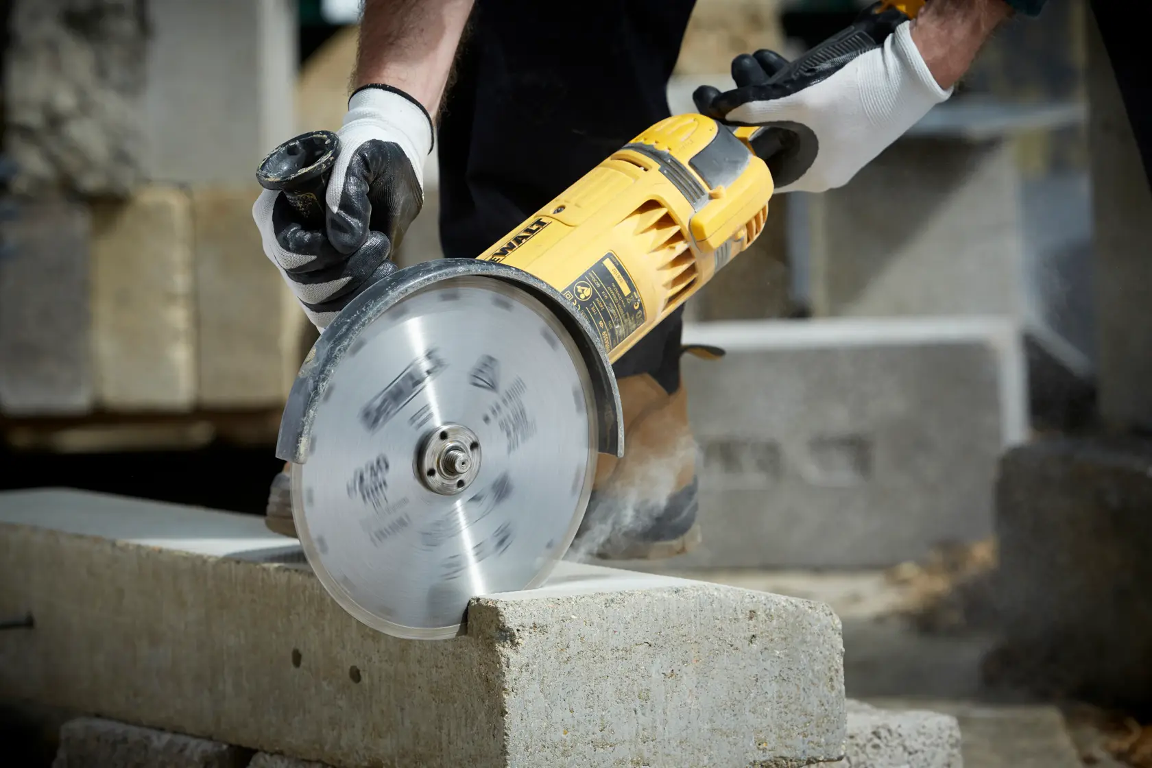 DEWALT DT3731 cutting concrete block with a rotary saw, operated by gloved hands in a construction setting.