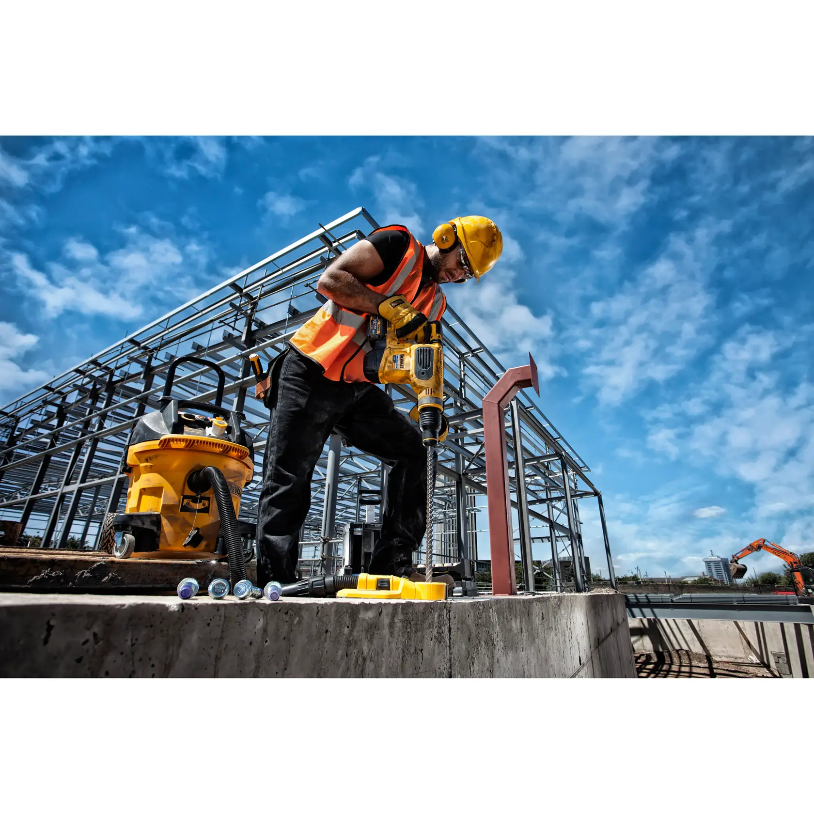 Trabajador perfora concreto con herramienta DEWALT en una presa bajo el sol.