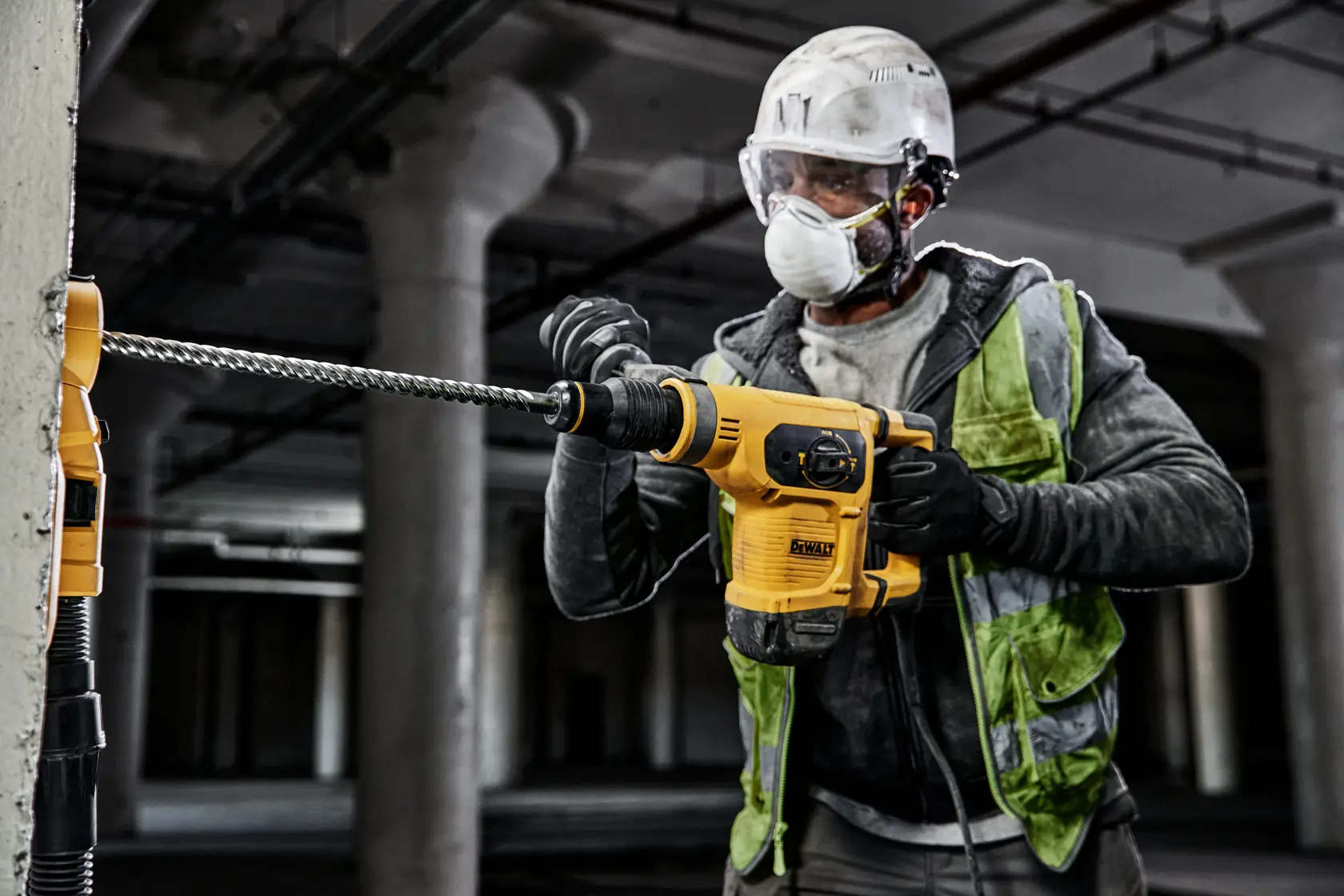 Trabajador utiliza un martillo DEWALT en pared de concreto, con equipo de seguridad industrial.