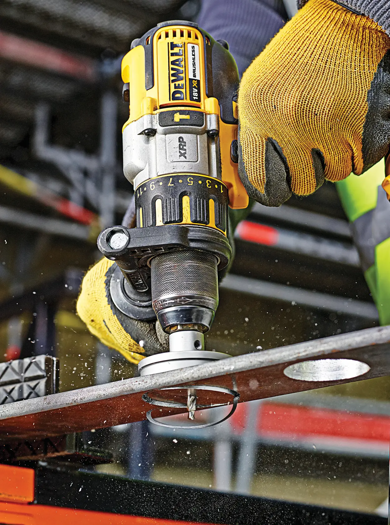 Worker uses DEWALT drill DT8353 to cut a hole in metal. Protective gloves and workshop background visible.