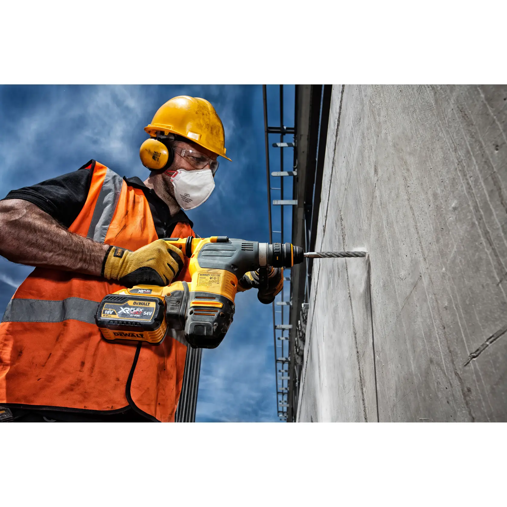 Arbeiter mit Schutzkleidung nutzt DEWALT Akku-Bohrmaschine, um draußen eine Betonwand zu bohren.