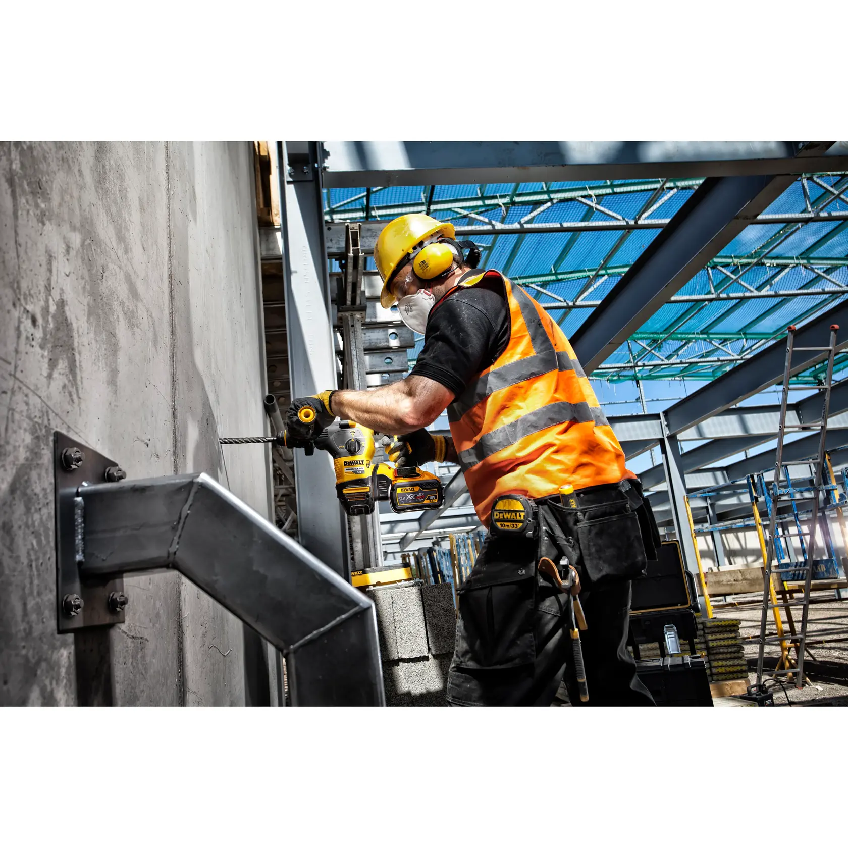 Arbeiter nutzt DEWALT-Bohrmaschine an Betonwand, Baustelle, orange Weste, Sicherheitsausrüstung.