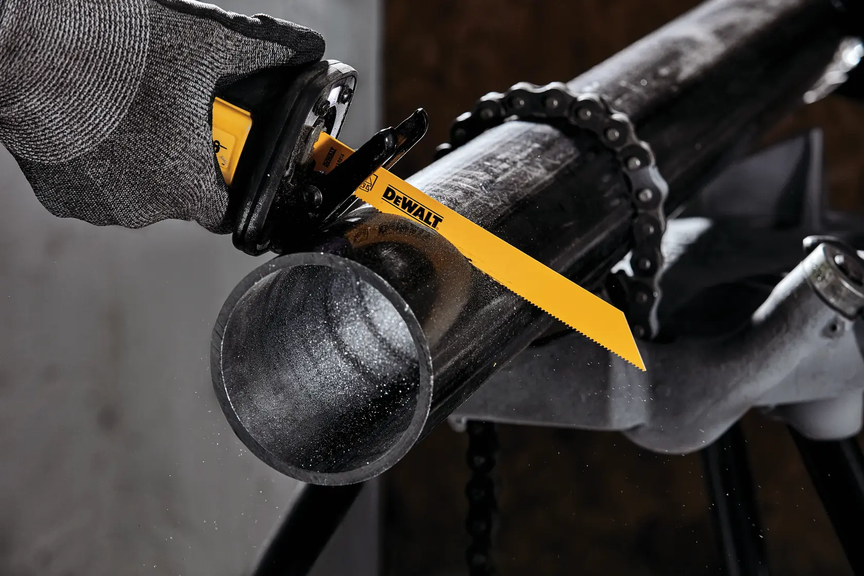 Photo of DEWALT DW4809 reciprocating saw blade cutting metal pipe, yellow blade, gloved hand visible.