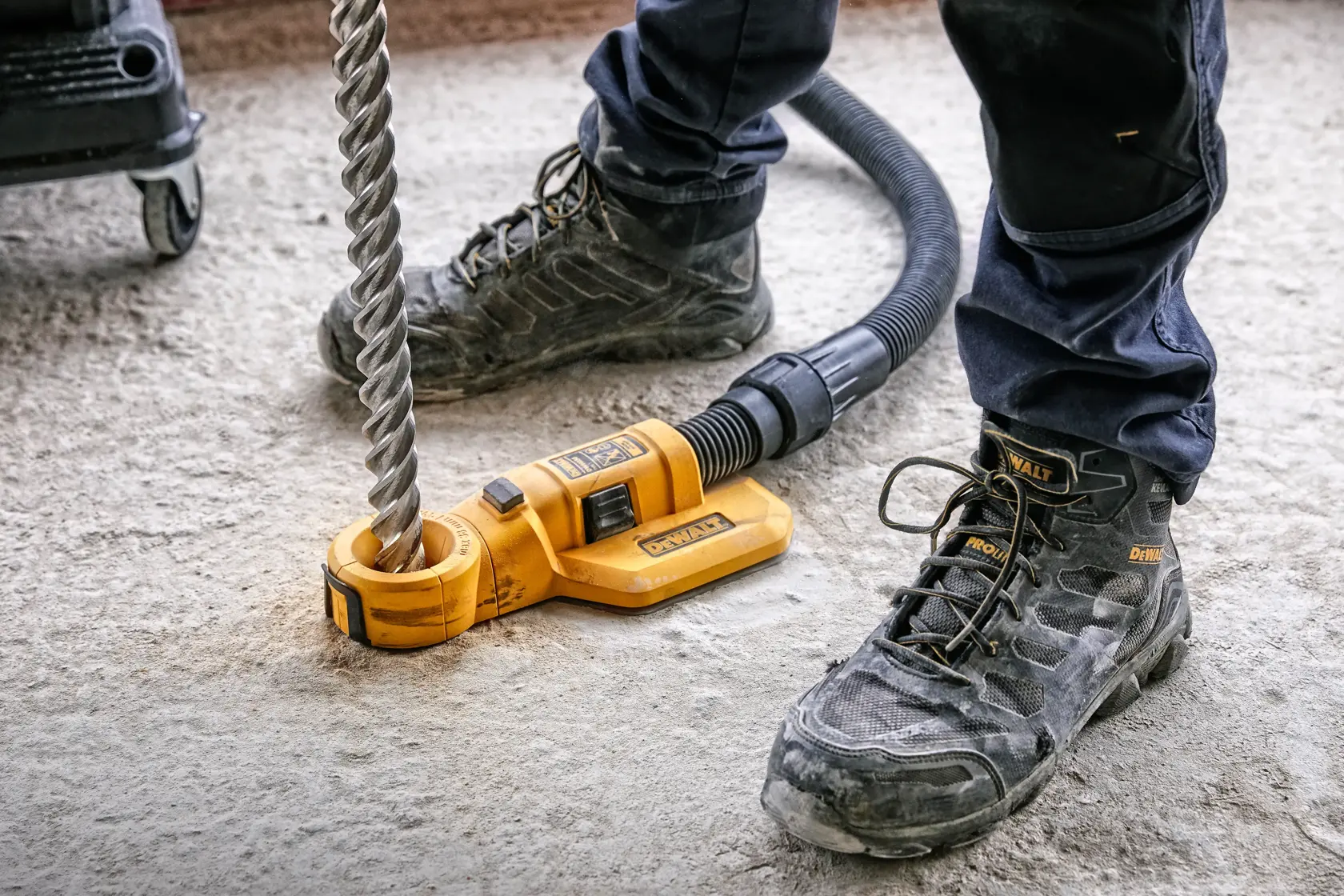 DEWALT-Bohrwerkzeug DWH050, DWH050K, DWH050-XJ im Einsatz auf Betonboden von Arbeiter mit Stiefeln.