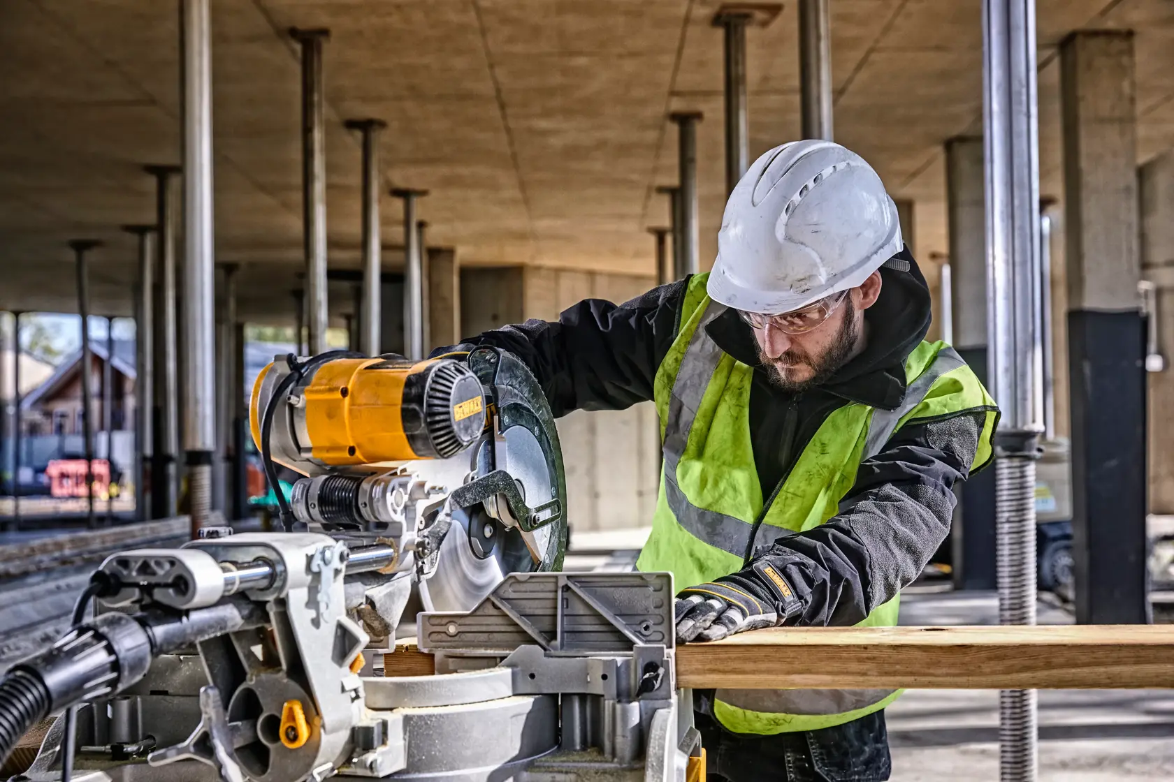 DEWALT DWS780, DWS780KIT miter saw in use at a building site. Worker cuts wood. Photography product category.