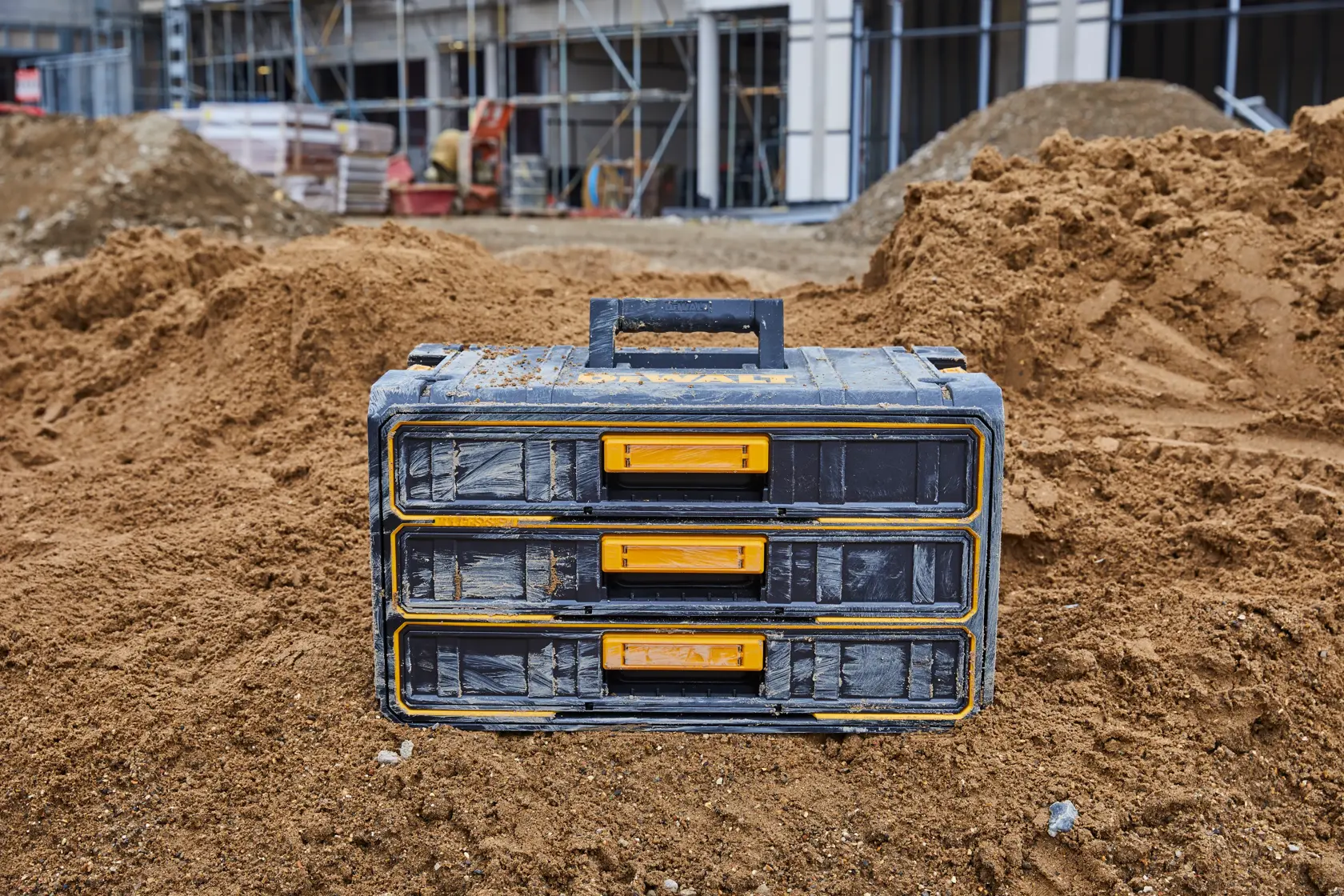 DEWALT tool storage box with drawers on a sandy construction site.