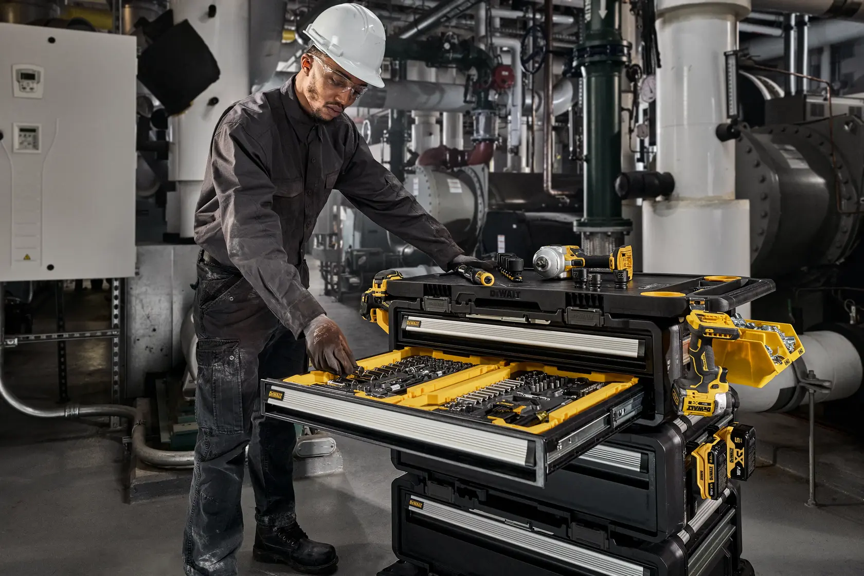 Photo of worker using DEWALT DWST60510-1 tool chest with open drawer in industrial setting.