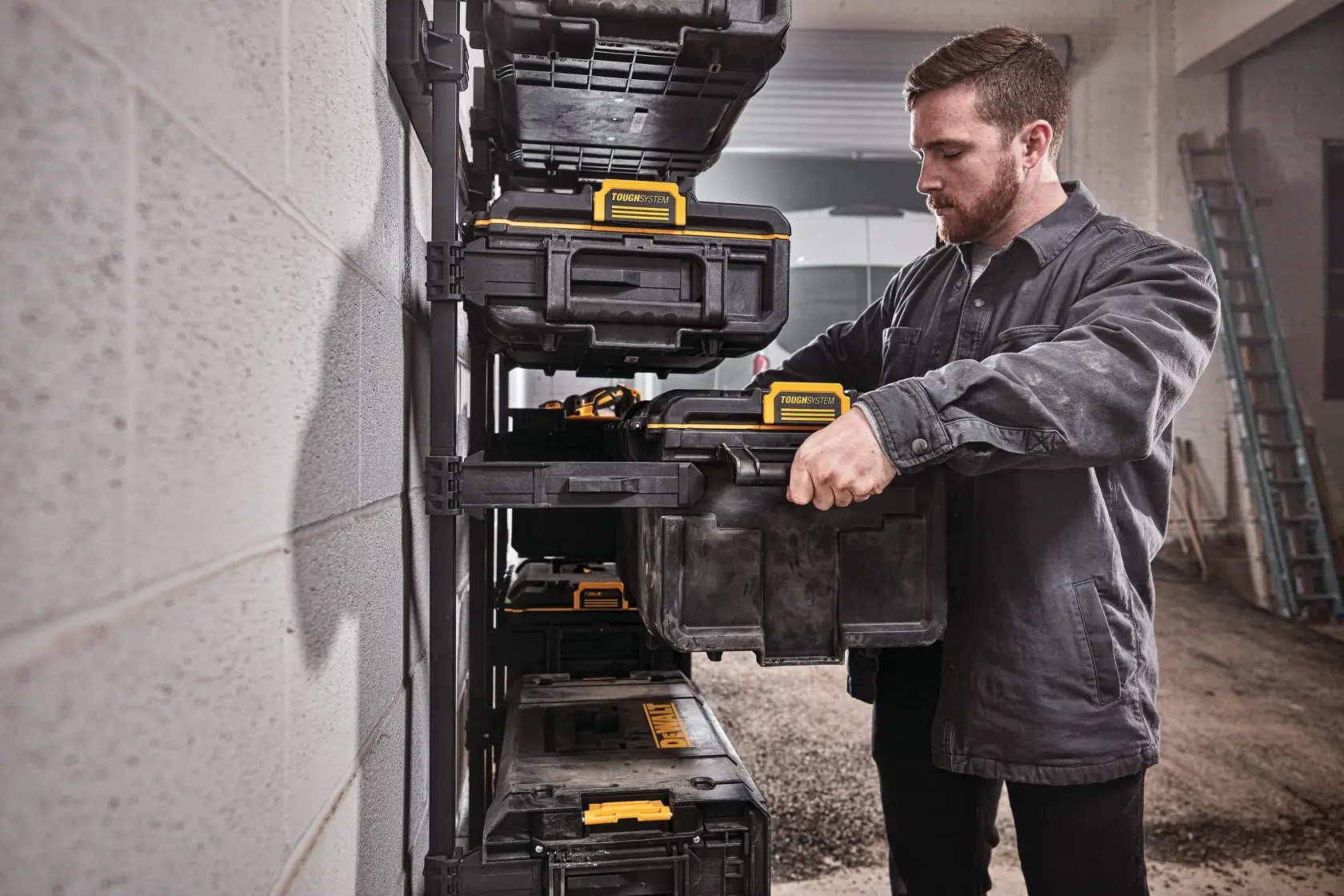 DEWALT ToughSystem 2.0 Werbegrafik mit dem Slogan 'Storage Built to Handle It' in großen, gelben Buchstaben auf einem dunklen, strukturierten Hintergrund.