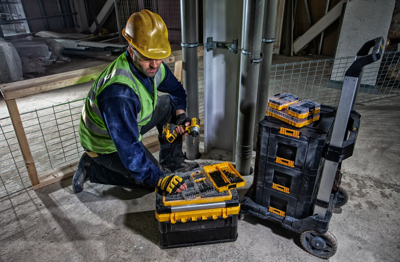 Un chariot roulant DEWALT avec une base en plastique noir, un cadre en métal argenté et quatre roues pivotantes. La plateforme comporte des mécanismes de verrouillage et une poignée relevée pour transporter des objets lourds.